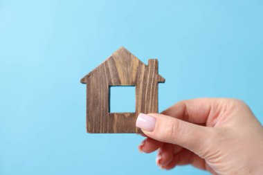 Ev güvenliği. Açık mavi arka planda ev figürlü kadın, yakın plan.