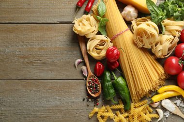 Farklı türde makarna ve malzemeler ahşap masada, düz yerde. Metin için boşluk