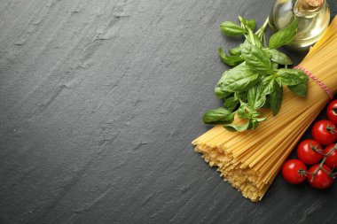 Çiğ spagetti makarnası ve siyah masa üzerinde farklı malzemeler. Metin için boşluk