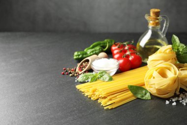 Farklı türde makarna ve malzemeler siyah masada, yakın plan. Metin için boşluk