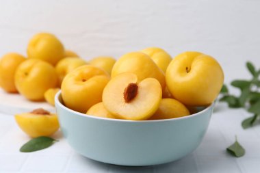 Beyaz fayanslı masada olgun sarı kiraz erikleri, yakın plan.