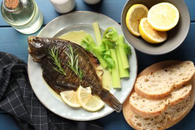 Mavi ahşap masada servis edilen kereviz balıklı kızarmış balık. Ev yapımı deniz ürünleri yemeği.