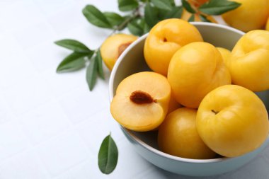 Beyaz fayanslı masada olgun sarı kiraz erikleri, yakın plan.