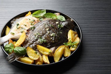 Siyah masada otlu ve patatesli kızarmış balık, yakın plan. Ev yapımı deniz ürünleri yemeği.