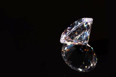 Siyah arka plana karşı ayna yüzeyinde parlak bir elmas, yakın plan. Metin için boşluk