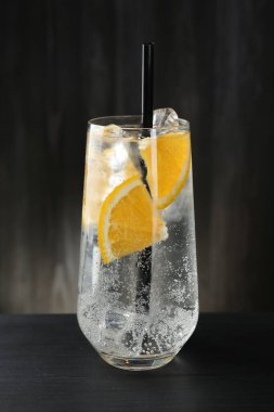 Portakal dilimli soda ve siyah ahşap masada buzlu cam.