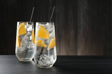 Portakal dilimli soda ve siyah ahşap masada buzlu bardaklar. Metin için boşluk