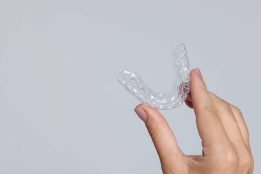 Gri arka planda diş hizalayan kadın, yakın plan. Metin için boşluk