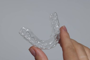 Gri arka planda diş hizalayan kadın, yakın plan.