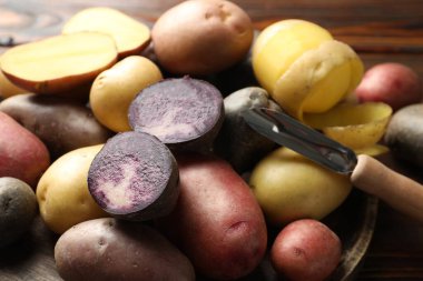 Masada farklı tipte patates ve soyucu var, yakın plan.