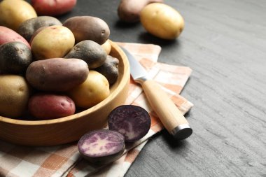 Farklı tipte patatesler kasede ve siyah masada bıçak, yakın plan. Metin için boşluk