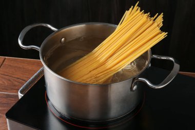 Taze tagliatelle makarnası tencerede kaynar su ve elektrikli soba, yakın plan.