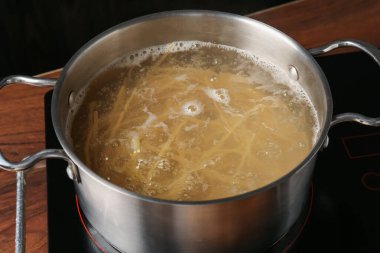 Taze tagliatelle makarnası tencerede kaynar su ve elektrikli soba, yakın plan.