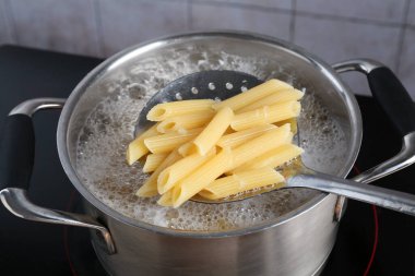Elektrikli ocakta kaynar suyla haşlanmış makarnadan makarna alıp yakın plan çekiyoruz.