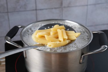 Elektrikli ocakta kaynar suyla haşlanmış makarnadan makarna alıp yakın plan çekiyoruz.