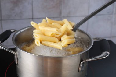 Elektrikli ocakta kaynar suyla haşlanmış makarnadan makarna alıp yakın plan çekiyoruz.