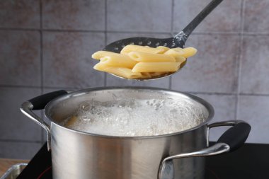 Elektrikli ocakta kaynar suyla haşlanmış makarnadan makarna alıp yakın plan çekiyoruz.