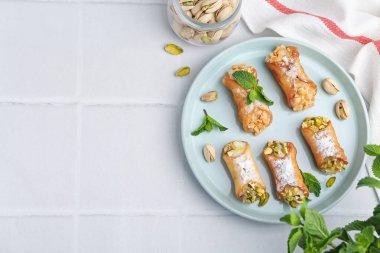Peynirli, fındıklı ve naneli nefis cannoli, beyaz fayanslı masa, düz yatak. Metin için boşluk