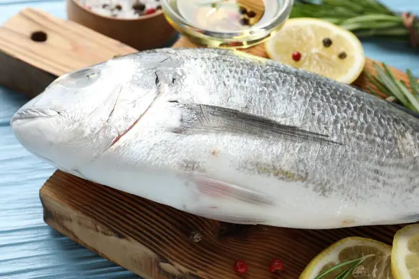 Mavi ahşap masadaki baharatlı taze çiğ dourade, yakın plan. Balık ve deniz ürünleri lezzetleri