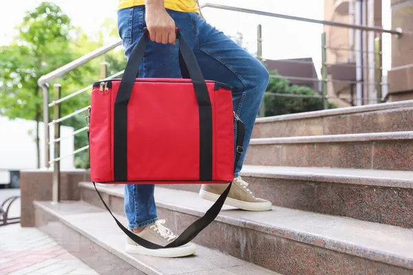 Dışarıdaki merdivenlerde termo çantalı kurye, yakın plan. Yemek dağıtım servisi.