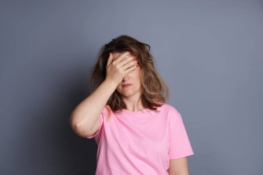 Gri arka planda akşamdan kalma bir kadın.