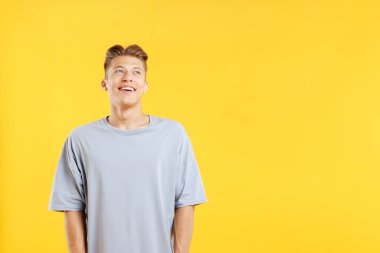 Hayaller gerçek oluyor. Pozitif genç adam sarı arka planda bir şeyler düşünüyor. Metin için boşluk