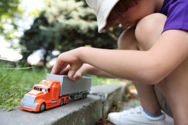 Küçük çocuk dışarıda oyuncak arabayla oynuyor, yakın plan.