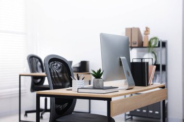 Ofisteki ahşap masa üzerinde modern bilgisayarı ve kırtasiyesi olan şık bir iş yeri.