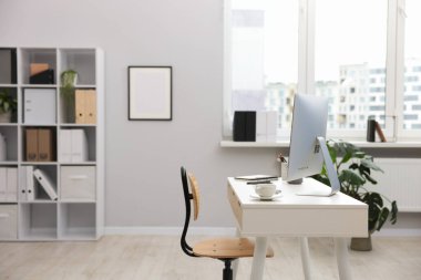 Ofisteki beyaz masa üzerinde modern bilgisayarı ve kırtasiyesi olan şık bir iş yeri.