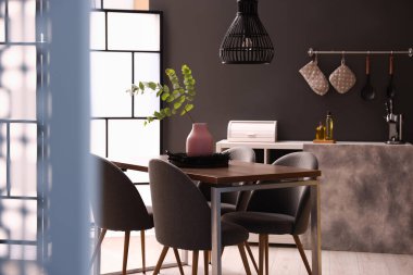 Tahta masa, yemek odasında sandalyeler ve çiçek dekoru var. İç tasarım