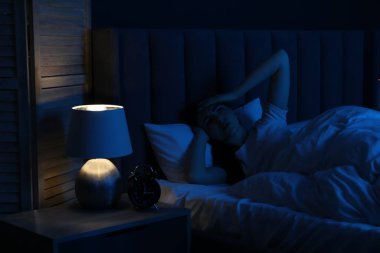 Evde yatakta uykusuzluk çeken hayal kırıklığına uğramış bir kadın.