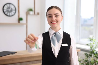 Gülümseyen resepsiyonistin portresi otelde misafir odasının anahtarını veriyor.