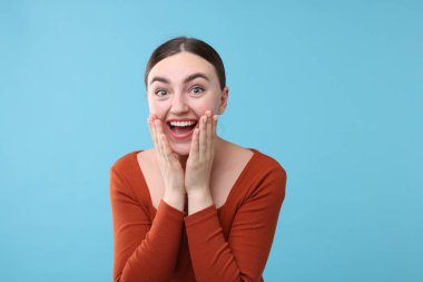 Açık mavi arka planda gülen güzel bir kadın. Pozitif duygu