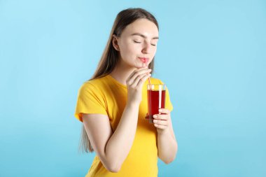 Açık mavi arka planda samandan meyve suyu içen kadın