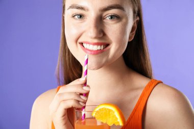 Menekşe arka planında canlandırıcı içecek ve saman olan kadın.