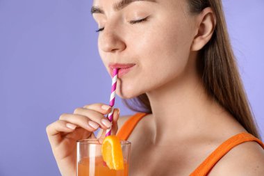 Kadın menekşe arka planında samandan ferahlatıcı içecek içiyor, metin için yer var.