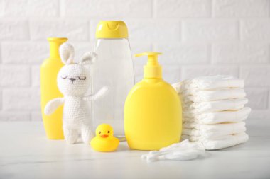 Duvarın yanındaki masada bir sürü bebek aksesuarı ve oyuncak tavşan var.