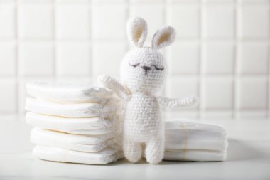 Bebek bezi ve oyuncak tavşan duvarın yanındaki beyaz masada.