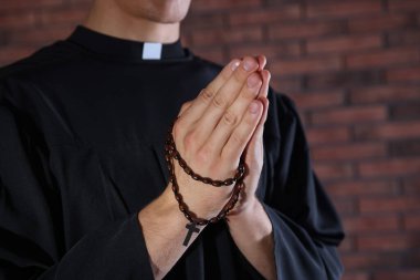 Tuğla duvarın yanında dua eden rahip, yaklaş.