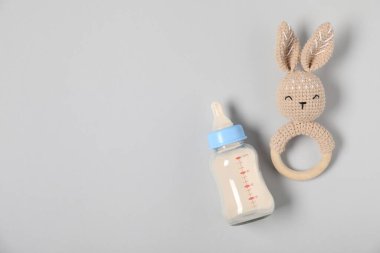 Gri arka planda formülü ve ipiyle beslenme şişesi düz yerde. Metin için boşluk