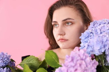 Pembe arka planda Hortensiya çiçekleri olan güzel bir kadın.