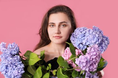 Pembe arka planda Hortensiya çiçekleri olan güzel bir kadının portresi