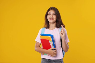 Not defterleri olan bir öğrenci turuncu arka planda şans diliyor. İyi bir sınav sonucu için umut