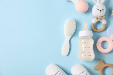 Açık mavi zemin üzerinde süt ve bebek aksesuarları olan bir şişe. Metin için boşluk