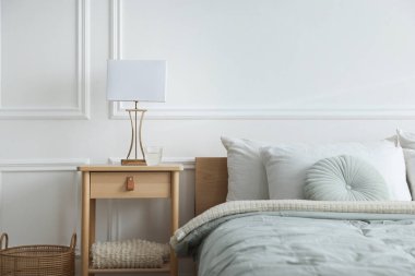 Yatak odasının yanında lamba ve bir bardak su olan komodinin yanında.