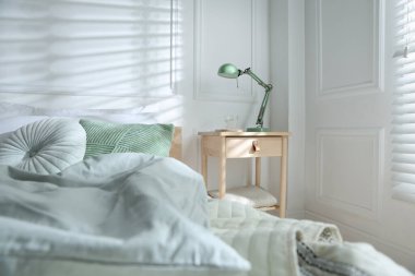 Yatak odasının yanında lamba ve bir bardak su olan komodinin yanında.