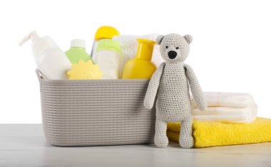 Beyaz arka planda farklı bebek aksesuarları ve oyuncak ayı var.