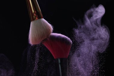 Siyah arka planda mor göz farlı makyaj fırçaları, yakın plan