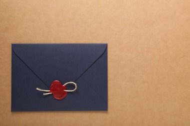 Üzerinde kırmızı balmumu mühür ve bej arka planda sicim olan güzel bir zarf, üst manzara. Metin için boşluk