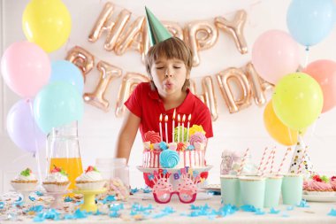 Doğum günü kutlaması. Şenlikli bir odada pasta masasında mumları üfleyen sevimli küçük çocuk.